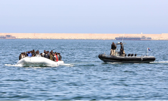 Libyan coast guards escort a boat carrying refugees and migrants