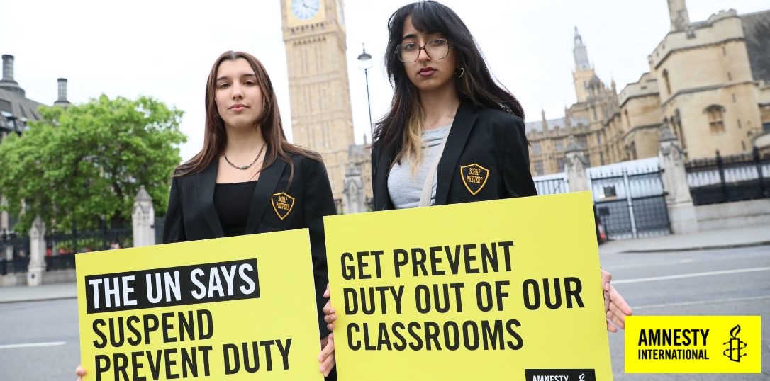 young activists hold banners saying "the un says suspend prevent duty" and "get prevent duty out of our classrooms"