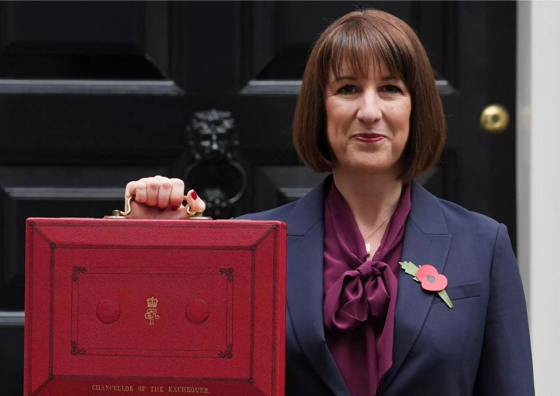 "chancellor rachel reeves, holds the red box up in her right hand whilst smiling"