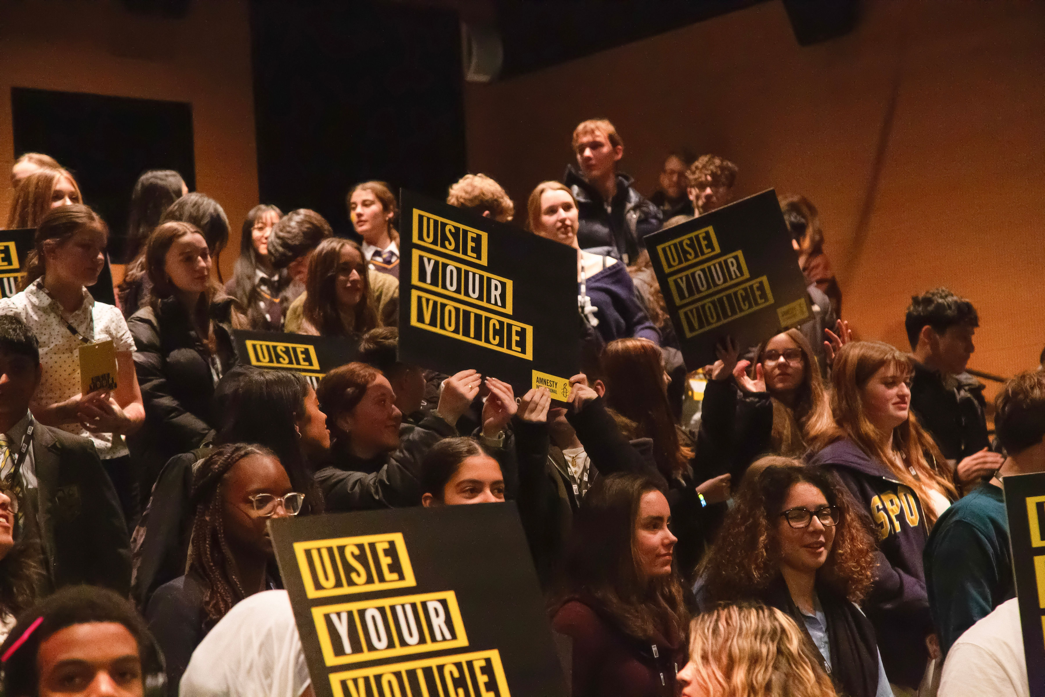 "people holding placards that read: use your voice"