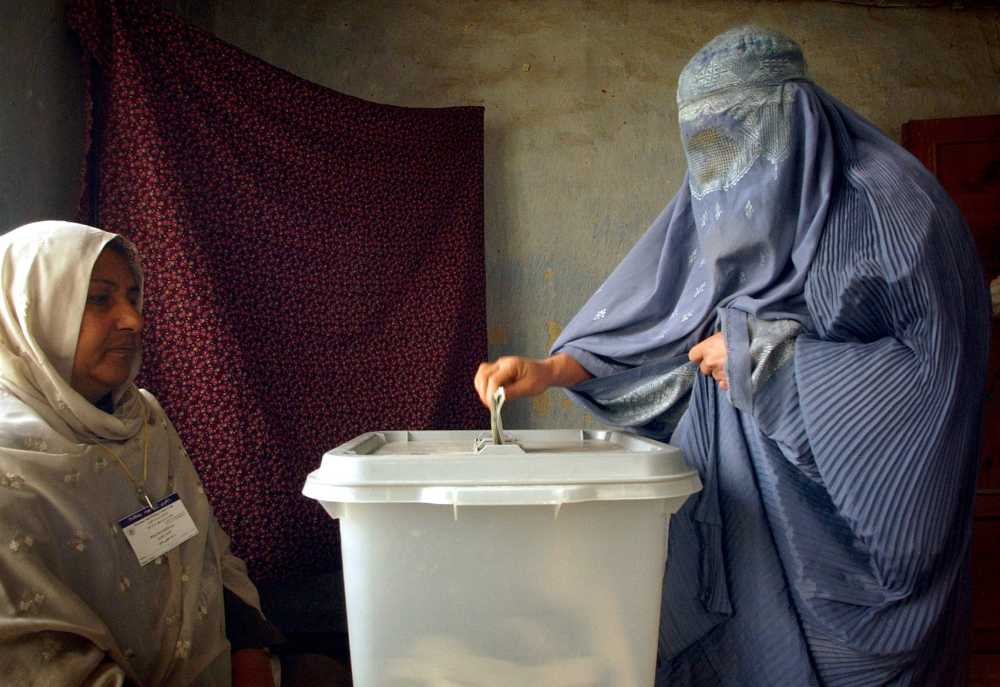 An Afghan woman wearing burqa casts her ballot at a polling station in Kabul Saturday, Oct. 9. 2004. Across Afghanistan voters went to the polls in the country's first-ever direct presidential elections.