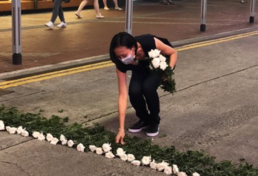 Image of Clara Cheung laying down white roses on the road