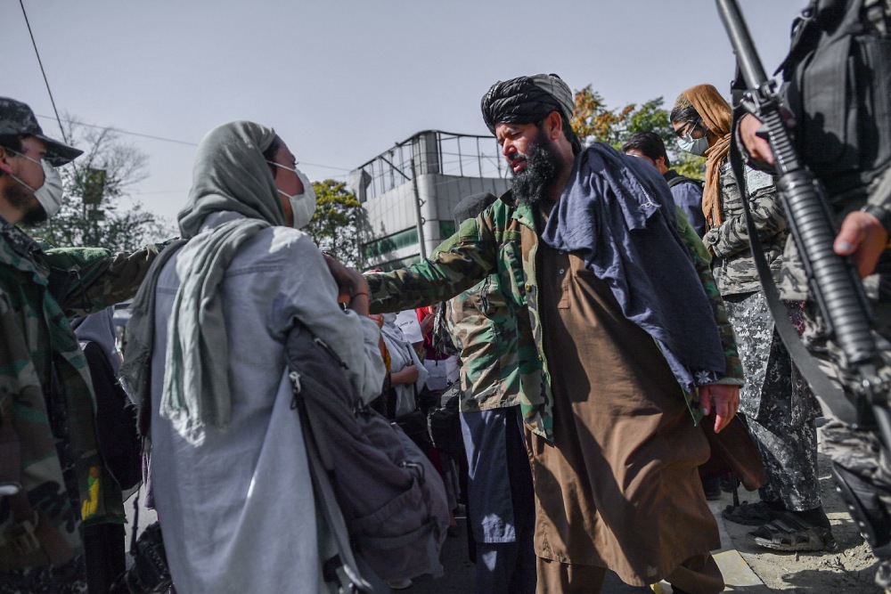 TOPSHOT - Taliban members stop women protesting for women's rights in Kabul on October 21, 2021. - The Taliban violently cracked down on media coverage of a women's rights protest in Kabul on October 21 morning, beating several journalists. (Photo by BULENT KILIC / AFP)