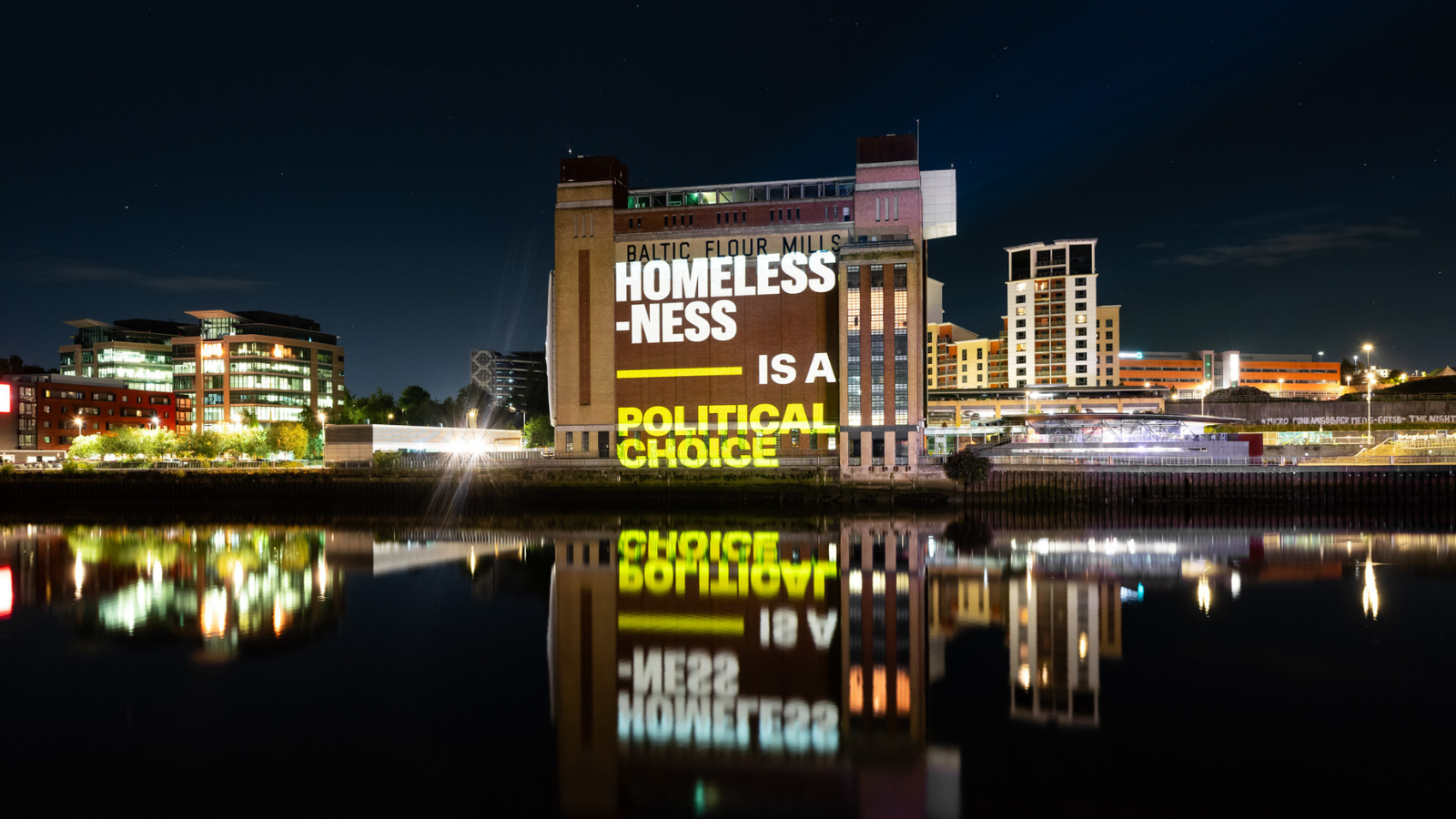 "projection overshadowed on river that reads: homelessness is a political choice"
