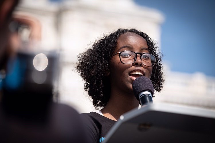 Isra address a crowd, microphone in hand