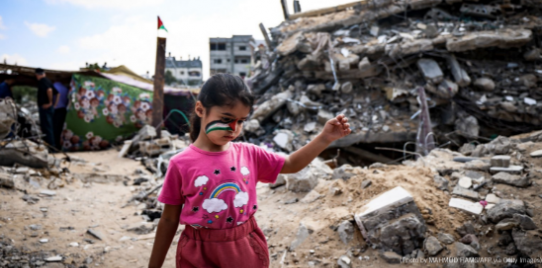 A Palestinian girl with a national flag painted on her face, plays amidst the rubble of buildings destroyed by Israeli bombardment of the Gaza Strip