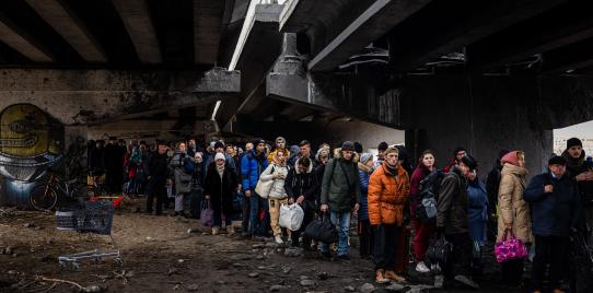 People take shelter under a damaged bridge in Ukraine