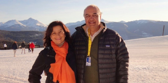 Morad Tahbaz & his wife stand smiling at camera, against a snowy landscape
