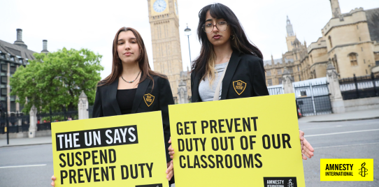 children hold signs that say "the un says suspend prevent duty" and "get prevent duty out of our classrooms"