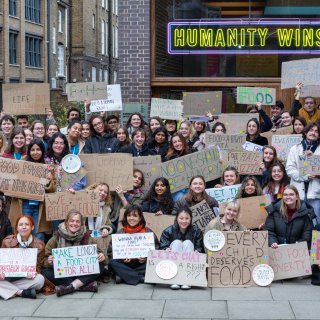 Amnesty Student Conference with lots of students holding signs up and posing for an image outside the Amnesty headquarters