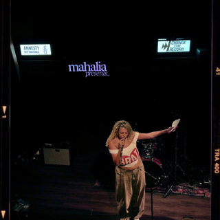 Mahalia stands on stage with 'change the record' behind her
