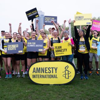 Amnesty runners at an event holding Team Amnesty placards