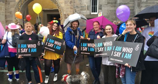 Amnesty Volunteers marching at Edinburgh Pride with trans rights placards saying 'I Am Who I Say I Am' 