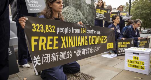 Image of Amnesty International supporters holding up signs that say '323,832 people from 184 countries say: free Xinjiang detainees'