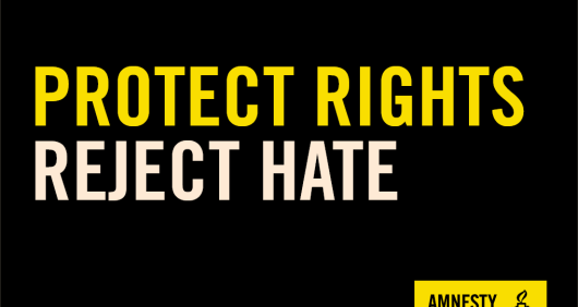 A black placard that reads Protect Rights, Reject Hate with an Amnesty logo in the bottom-right corner