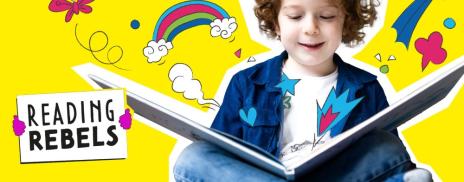 A child reading a book which has graphics of butterflies and rainbows coming out of it.