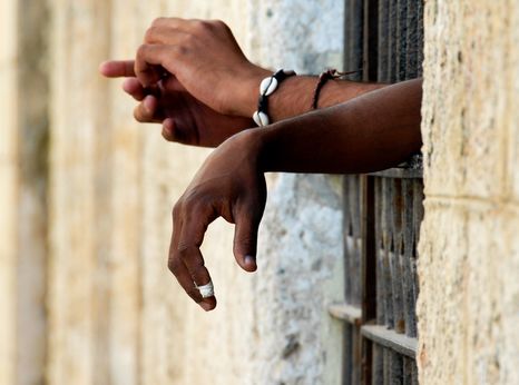 Hands reaching out from prison bars (c) John Woodworth