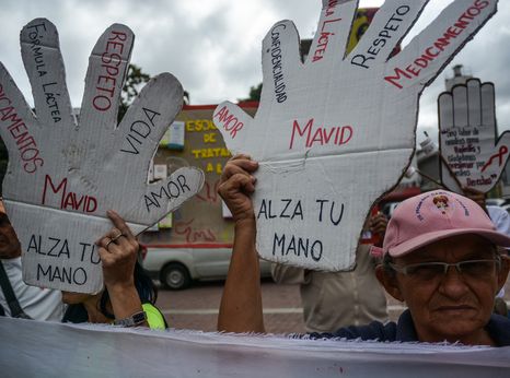 A group of people in need of treatment show their boards demanding Access to health care and medicines at the protest 