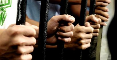 Photograph showing hands holding on to prison cell bars taken at the launch event for Amnesty International’s torture report - Above the Law: Police Torture in the Philippines