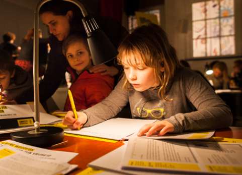 Young woman writes a letter beneath lamp