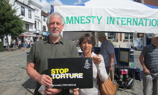 Couple holding up "Stop Torture (AI)" placard. Couple holding up "Stop Torture (AI)" placard.