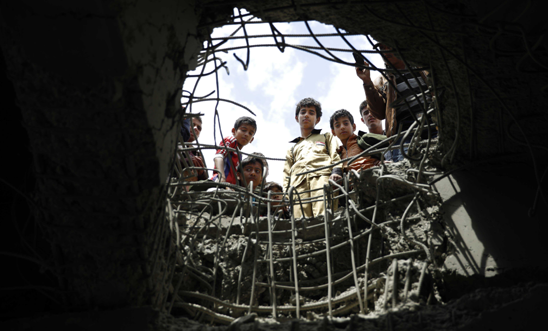 Wednesday, March 23, 2016 - boys look through a hole made by a Saudi-led airstrike on a bridge in Sanaa, Yemen © AP Photo/Hani Mohammed