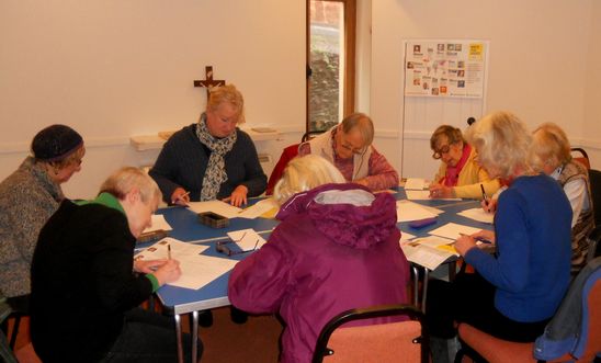 People sitting around a table writing letters