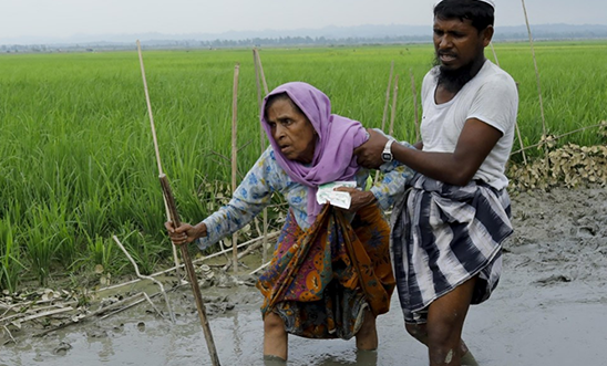 A Rohingya woman is helped to safety