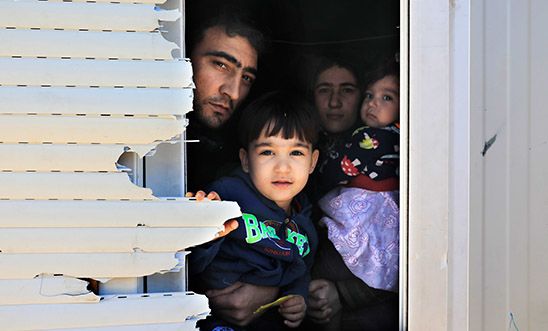 A family peeks through the window of the shipping container that is their temporary home A family peeks through the window of the shipping container that is their temporary home