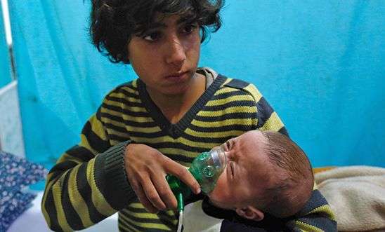 A Syrian boy holds an oxygen mask over the face of an infant at a make-shift hospital following a reported gas attack on the rebel-held besieged town of Douma in the eastern Ghouta region on the outskirts of the capital Damascus on January 22, 2018.