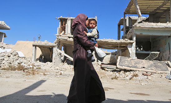 A Syrian woman heads to a medical centre to have her child examined by doctors on October 29, 2017, in Al-Nashabiyah in the besieged rebel-held Eastern Ghouta region outside Syria's capital Damascus.