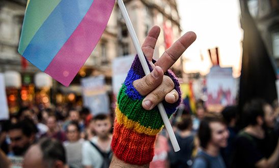 A LGBT member makes a victory sign with his fingers as he holds a rainbow flag on 21 August 2016 in Istanbul