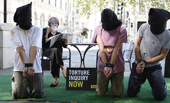 A stunt outside Downing street depicting Theresa May ignoring torture victims kneeling in front of her. A stunt outside Downing street depicting Theresa May ignoring torture victims kneeling in front of her.