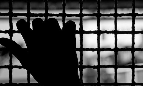 Freedom - image of a hand on cage, fingers on prison bars