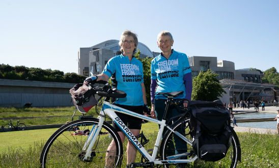 Image shows two women and a bicycle outside the Scottish Parliament