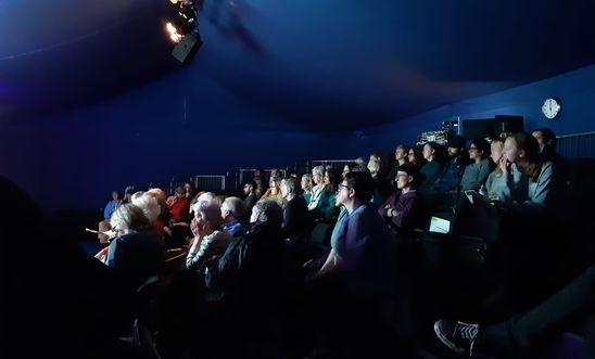 Image shows an audience in a darkened theatre Image shows an audience in a darkened theatre