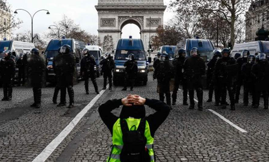 A protester kneeling in front of riot police in Paris, France. 