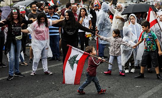 Boy carrying Lebanese flag past protesters