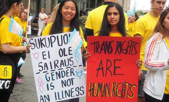 Young Amnesty activist hold placards, reading "trans rights are human rights".