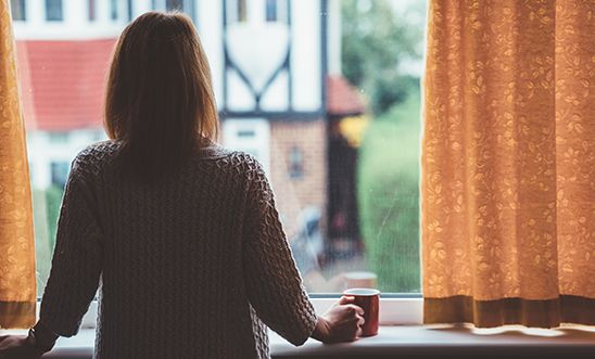 Rear view of woman at home staring through the window Rear view of woman at home staring through the window