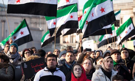 Women, men and children at a rally in London, UK carrying Syria flags
