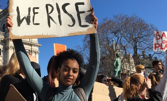 Young people hold up protest signs that read "We rise" Young people hold up protest signs that read "We rise"