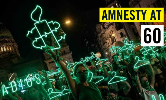 At an abortion protest a woman holds a green LED Amnesty Logo high