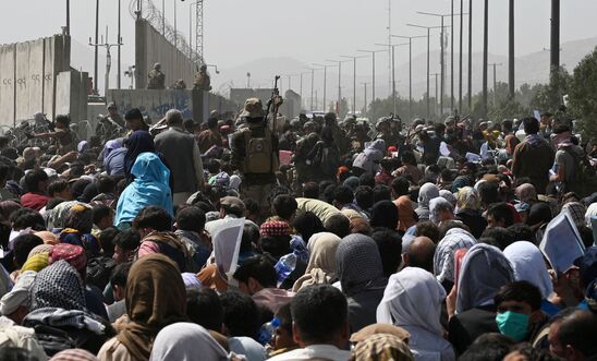 Afghans gather on a roadside near the military part of the airport in Kabul on August 20, 2021, hoping to flee from the country after the Taliban's military takeover of Afghanistan.