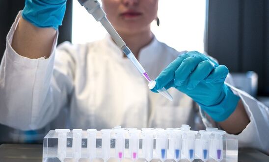 Female scientist in laboratory researches Covid vaccine, using a pipette and test tube