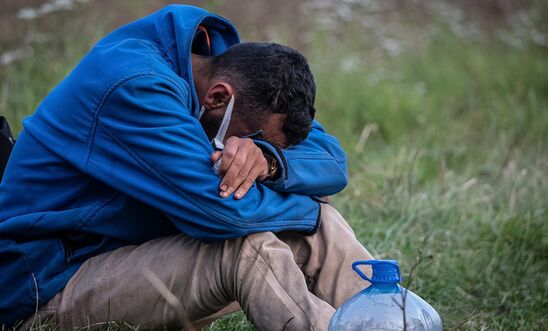 Afghan asylum seeker is pictured distressed, sitting with his head in his hands at the Poland-Belarus border. Image taken last month.