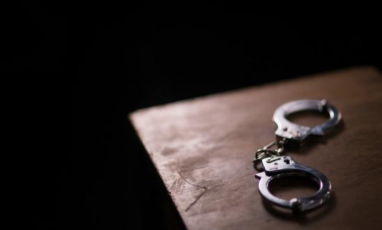 Handcuffs lie on a table with a black background Handcuffs lie on a table with a black background