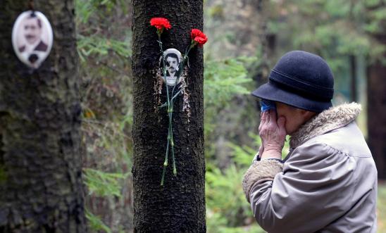 A woman reacts next to a portrait of a victim of Soviet dictator Joseph Stalin's purges at the memorial, where the victims were buried in the woods on the outskirts of Saint-Petersburg, on October 30, 2017. A woman reacts next to a portrait of a victim of Soviet dictator Joseph Stalin's purges at the memorial, where the victims were buried in the woods on the outskirts of Saint-Petersburg, on October 30, 2017.