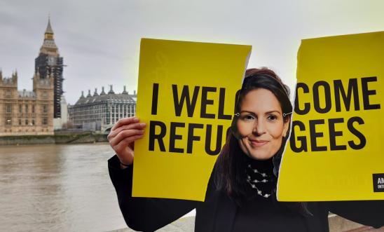 Priti Patel look-alike tears up a 'I Welcome Refugees’ sign