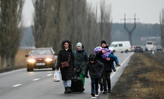 Refugees from Ukraine walk a road after crossing the Moldova-Ukrainian border's checkpoint near the town of Palanca on March 1, 2022